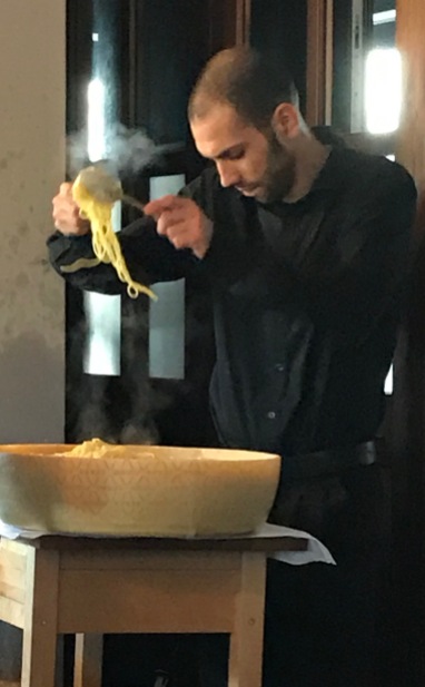 The chef is mixing the noodles with cheese.